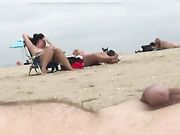 Un hombre nudista eyacula en la playa mientras dos mujeres lo miran